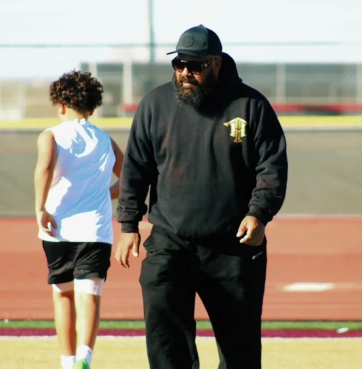 Trench House coach guiding a young lineman through a drill