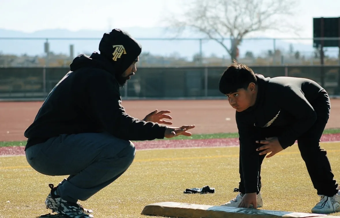 Coach working one-on-one with a young lineman on the field